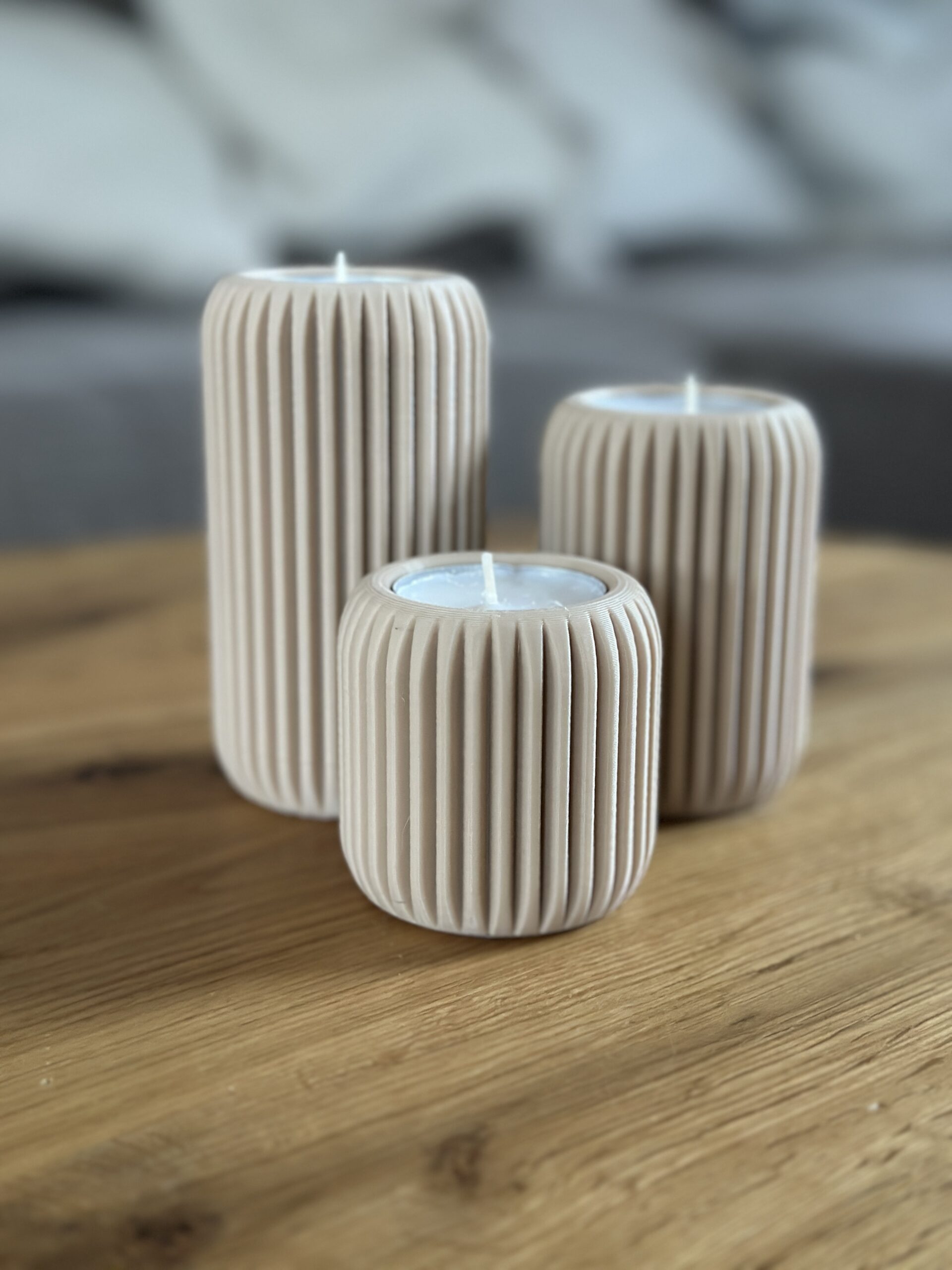 Drei graue Teelichthalter Lunes aus 3D Druck stehen minimalistisch auf einem Holztisch.