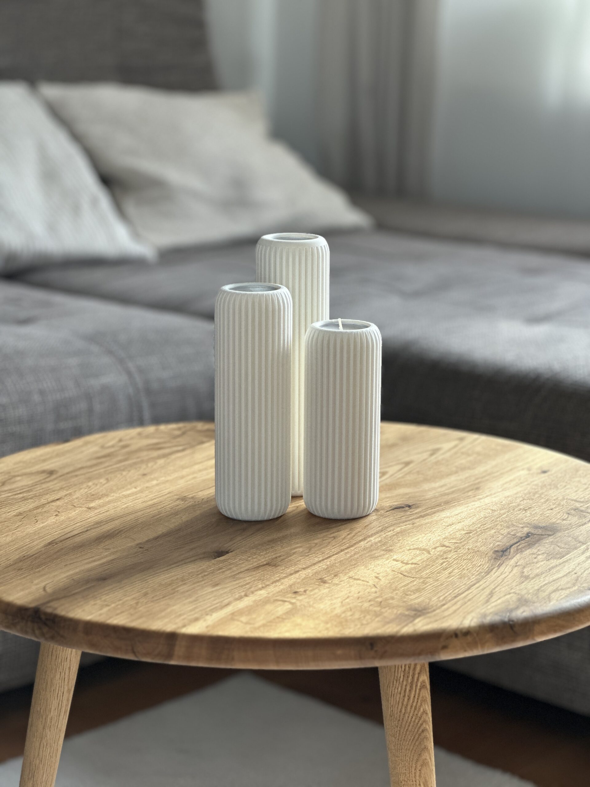 Drei weiße Teelichthalter Lunes aus 3D Druck stehen minimalistisch auf einem Holztisch.